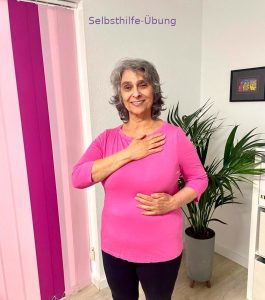 Frau zeigt Jin Shin Jyutsu Selbsthilfe-Übung mit Handposition an Brust und Bauch zur Stärkung der Lungenenergie