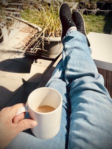 Beine hochlegen und eine Tasse Kaffee genießen als Symbol für Selbstfürsorge und bewusstes Innehalten im Alltag.