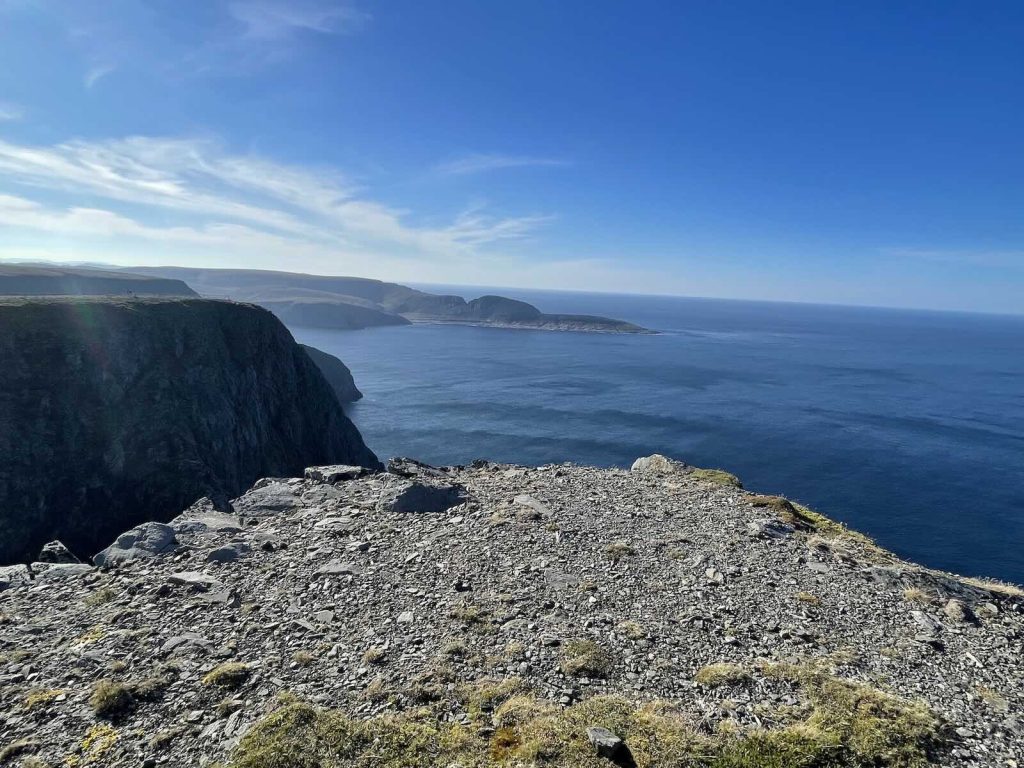 Felsküste am Nordkap auf Magerøya mit Blick über das tiefblaue Nordmeer bis zum Horizont unter klarem Himmel.